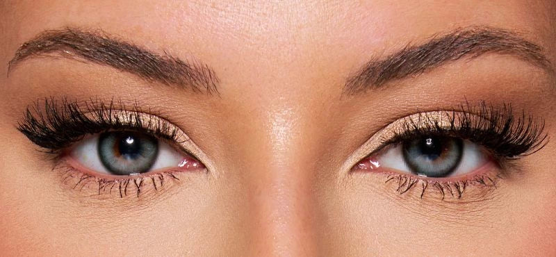 Front view of a model wearing teal blue colored contact lenses paired with dramatic lashes and soft glam makeup – a bold, mesmerizing look by KIISBEAUTY.