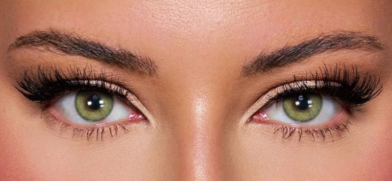Front view of a model wearing vibrant green colored contact lenses paired with dramatic lashes and soft glam makeup – a bold, mesmerizing look by KIISBEAUTY.