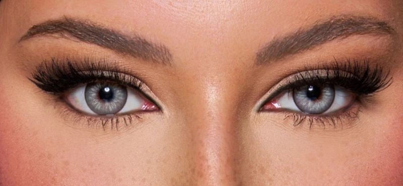 Front view of a model wearing icy grey colored contact lenses paired with dramatic lashes and soft glam makeup – a bold, mesmerizing look by KIISBEAUTY.