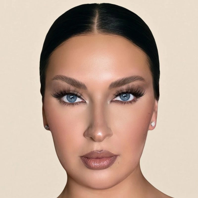 Front view of a woman with blue eyes wearing voluminous KB Lashes and flawless nude makeup